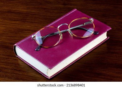 Old book and spectacles on a polished wooden surface