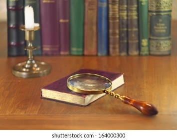 old book with vintage magnifying glass and candle - Powered by Shutterstock