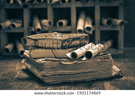 Old books and antique scrolls in library on wooden table