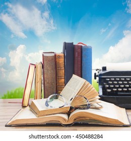 Old Books, Glasses And Typewriter Over Sky And Grass Background - Writting And Publishing Concept