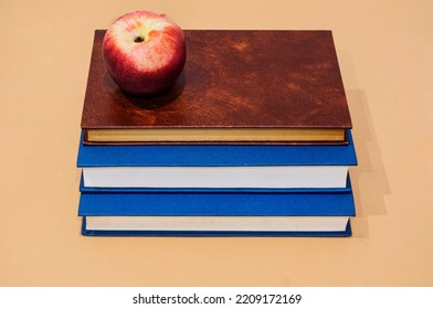 Old Books On A Plain Background With A Red And Yellow Nectarine Garnished With Tiny Water Droplets