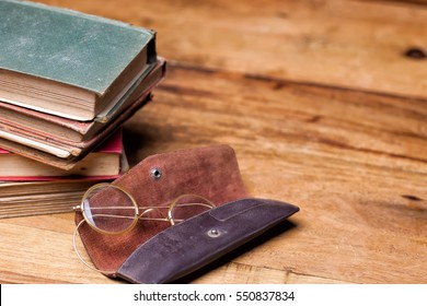  old books on the wooden bookshelf, vintage eyeglasses in leather case