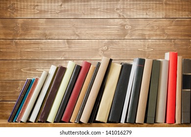 Old books on a wooden shelf. No labels, blank spine.