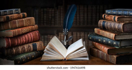 Old books ,quill pen and vintage inkwell on wooden desk in old library. Ancient books historical background. Retro style. Conceptual background on history, education, literature topics.