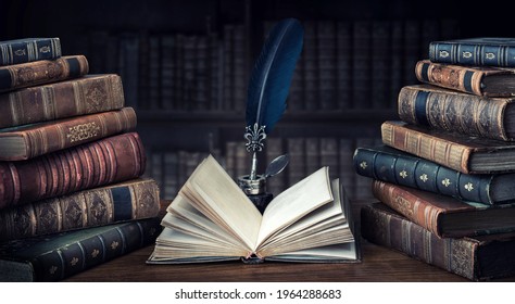 Old books ,quill pen and vintage inkwell on wooden desk in old library. Ancient books historical background. Retro style. Conceptual background on history, education, literature topics.