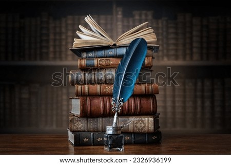 Old books ,quill pen and vintage inkwell on wooden desk in old library. Ancient books historical background. Retro style. Conceptual background on history, education, literature topics.
