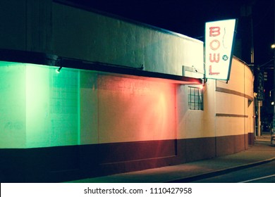 An Old Bowling Alley Exterior Lit Up With Green And Red Lighting And A Neon Sign At Night Showing The Sidewalk Leading Out Of The Frame