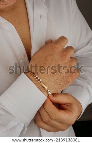 old bracelet in a man's hand, men's jewelry, a man in a white shirt