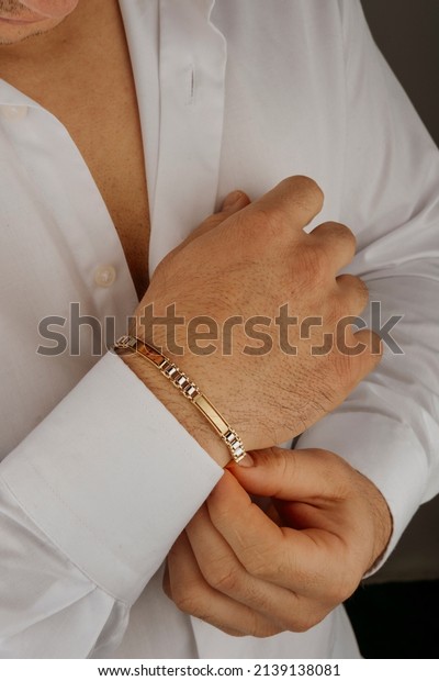 old bracelet in a man\'s hand, men\'s jewelry, a man\
in a white shirt