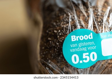 Old bread in a plastic package with a discount sticker in Dutch saying Brood van gisteren, vandaag voor meaning 'Yesterdays bread, today for', supermarket sale to reduce food waste in The Netherlands