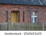 old brick abandoned house in the countryside with a view of a wooden fence, old electrical connection, old wooden door and window