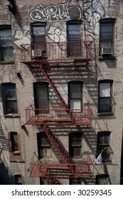 old brick apartment building with fire escape and graffiti., new york city