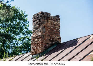 Old brick chimney in need of repair on a roof. Heating and fire safety concept.