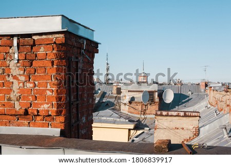 Old brick chimney pipe on a roof of residential building with copy space, satellite dish or 4g antenna installation