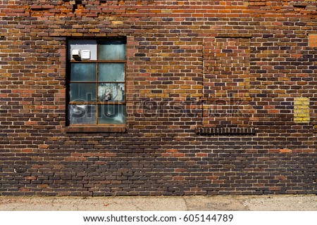 Old brick wall with brick filled window.