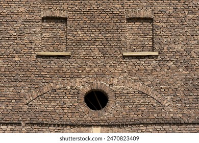 Old brick wall with round window, detail of an ancient building
