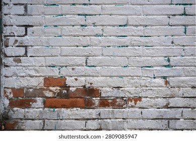 Old brick wall texture with peeling white paint and exposed red brick