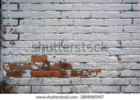 Old brick wall texture with peeling white paint and exposed red brick