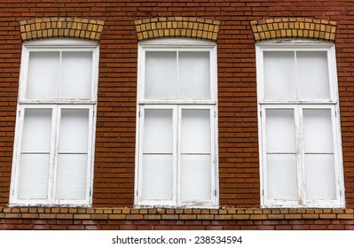 An old brick wall with three windows.