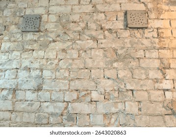 old brick wall with two ventilation grilles