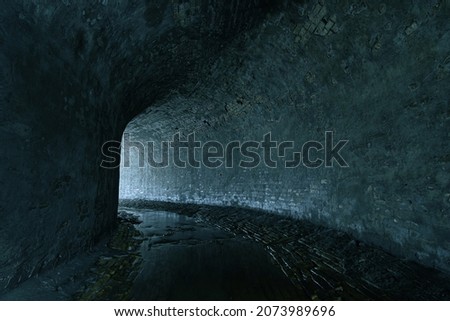Old brickwork sewer tunnel with light from the turn. Underground river or old rainwater collector of the 19th century.