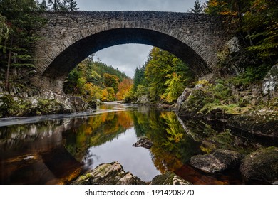 The old bridge at Darnaway, Moray, Scotland. The bridge is photographed in autumn to capture the colours and also the reflection of the bridge curves in the water.