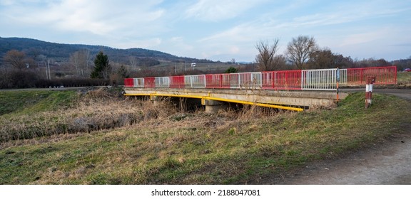 Old Bridge Over Stream With Red And White Railings.