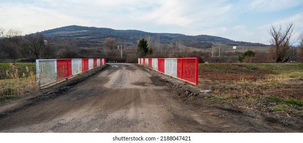 Old Bridge Over Stream With Red And White Railings.