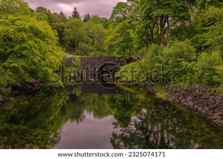 OLD BRIDGE AND WATERWAY ILINES WITH NICE GREEN FOLIAGE N THE TOWN OF LOCHINVER IN LAIRG SCOTLAND