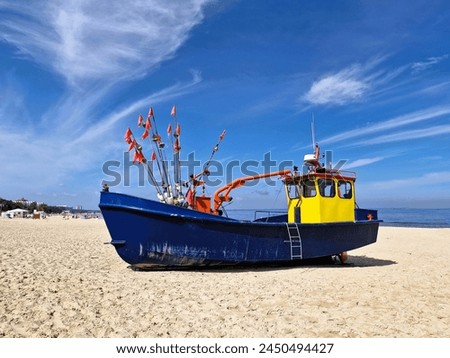 An old broken blue fishing boat stands on a sandy beach in Miedzyzdroje, Poland. Just an attraction for tourists to take pictures.