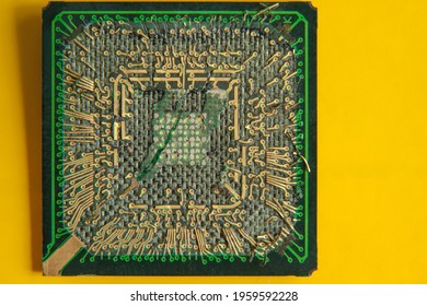 An Old Broken Computer CPU With A Torn Chip On A Yellow Background. Close-up