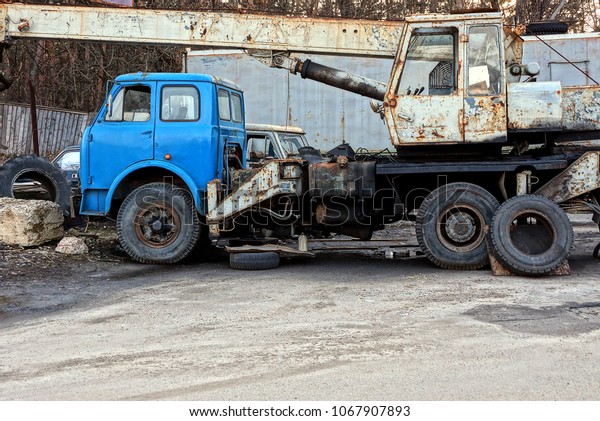 old broken industrial car with a crane stands on
the asphalt