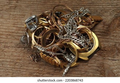 Old And Broken Jewelry, Watches Of Gold And Silver On A Wooden Texture. A Scrap Of Gold. 