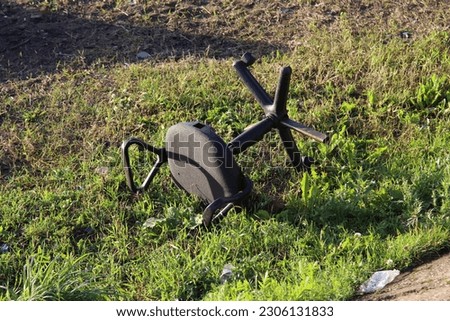 old broken office chair lying upside down on the green grass