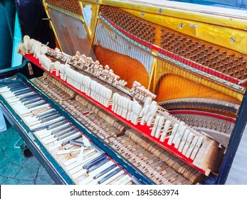 An Old Broken Piano With A Missing Wall And Cover And Broken Keys