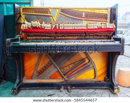 An old broken piano is on the street. Front view