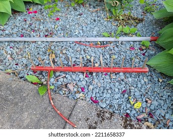 An Old And Broken Rake Sitting On Some Crushed Rock.