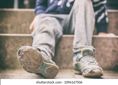 Alte gebrochene Schuhe eines kleinen Jungen als Symbol für Kinderarmut