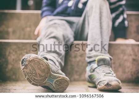 Old broken shoes of a little boy as a symbol for child poverty