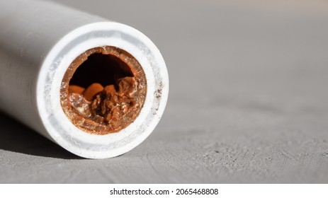 Old Broken Sludge Plumbing Polypropylene Pipe With Red Rust And Limescale On Concrete Background With Copy Space. Corrosion, Sludge, Limescale And Hard Water Concept