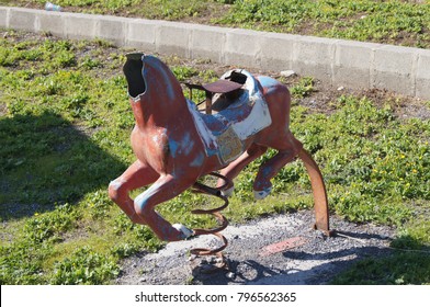 Old Broken Toy Horse On Spring Without Head On Children Playground. Apocalyptic Background. Color Phography.