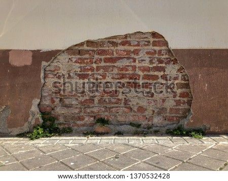 Old broken wall. Broken wall showing the structure made of bricks. Bicolor wall with a hole in the paint showing red bricks underneath.