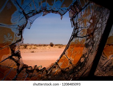 Old Broken Windsheild Of A Deserted Car, Looking Out On To A Desert Landscape