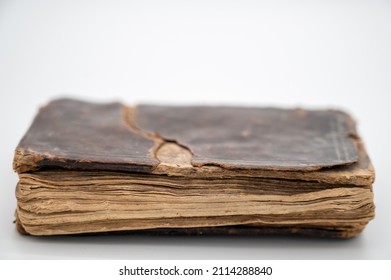 An Old Brown Book Sits Facing Us Closed With Leather Cover Concealing The Old English Words Printed Within. The Edges Of Pages Are Protruding From Beneath The Cover.