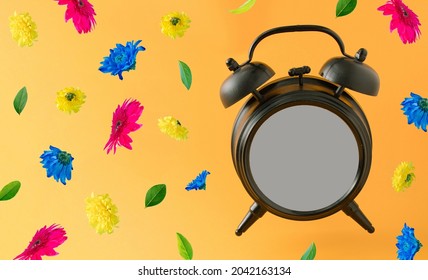 Old Brown Clock With Blank Space And Colorful Spring Flowers Flying On A Orange Background. Positive News, Thinking And Energy Concept. Optimistic Future, Mood And Atitude. Limited Time Offer Concept.