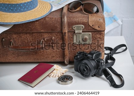 Old brown vintage suitcase with straw hat, photo camera, sunglasses, passport and a map, travel and summer vacation concept, copy space, selected focus, narrow depth of field