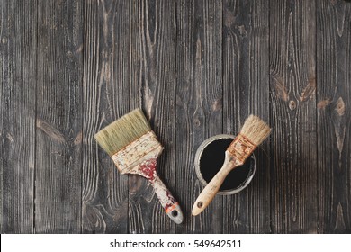 Old Brushes And Paint Cans Black On The Aged Table