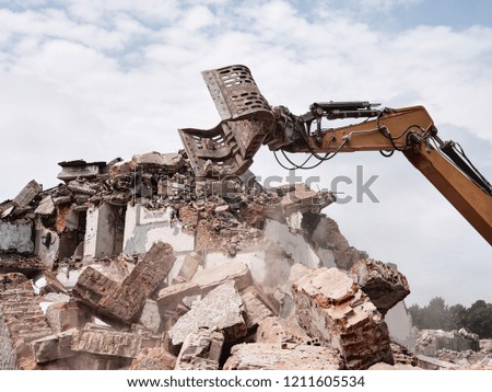 Old building demolition. Excavator working in rubble.