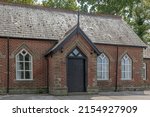 Old building with ornate wooden black door made of red bricks and sandstone blocks used as a village hall