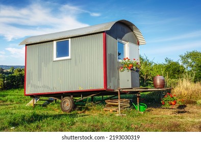 Old Building Trailer As Tiny House With Flowers In Rural Landscape 